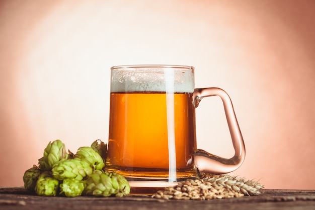 Glas bier met hop en gerst op de houten tafel