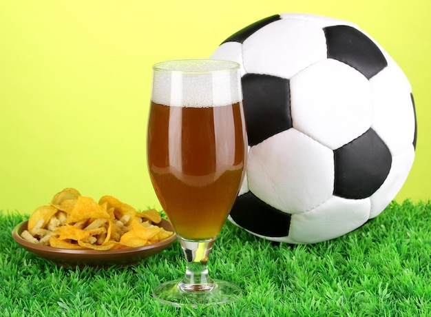 Glas bier met voetbal op gras op groene achtergrond