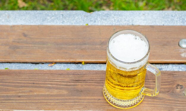 Foto glas bier op parkbank in openbaar park groen natuur lente zomer mobiele telefoonsmartphone