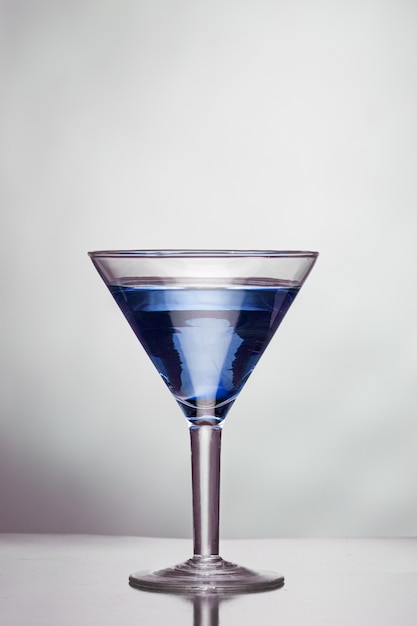 Glas blauwe alcoholische drank op een witte muur