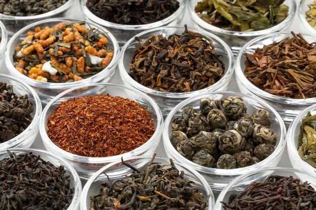 Photo glas bowls with a variaton of different dried tea leaves close up full frame