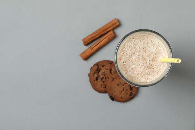 Glas chocolade milkshake, koekjes en kaneel op grijze achtergrond