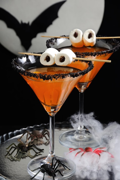 Glas citrus martini versierd met zwarte suiker met marshmallow-ogen op tafel in Halloween