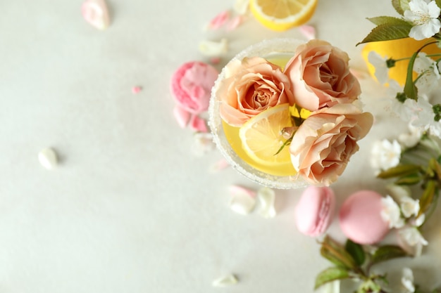 Glas cocktail, ingrediënten en bloemen op witte geweven lijst