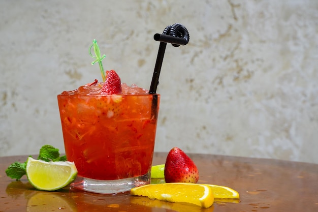 Glas cocktail met ijsblokjes en sinaasappelschil met rond fruit