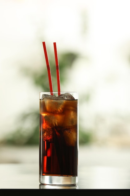 Glas cola met ijs op tafel tegen onscherpe achtergrond