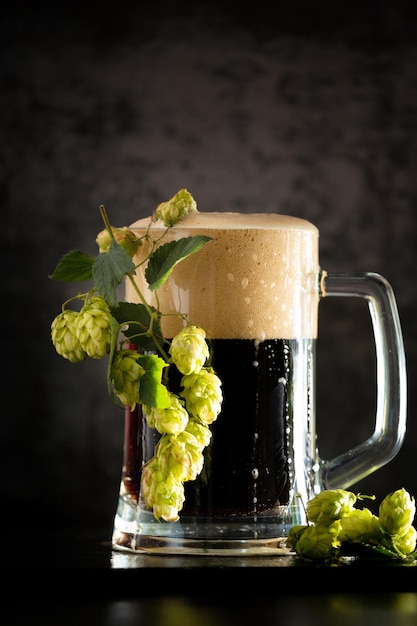 Glas donker bier met hop rond op een donkere achtergrond