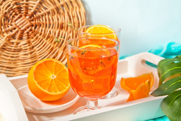 Glas en fles met verse zelfgemaakte oranje zoete ijsthee of cocktail, limonade met tijm. Verfrissend koud drankje. Zomerfeest.