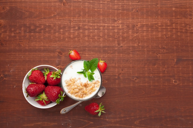 Glas gezonde aardbeiyoghurt met verse bessen op de houten mening van de lijstbovenkant