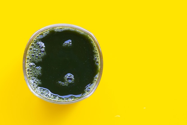 Glas gotuola verlaat sap voor gezondheid op gele achtergrond. Ruimte kopiëren