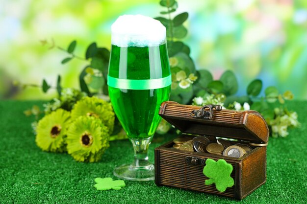 Foto glas groen bier en waterkruik met muntstukken op grasclose-up