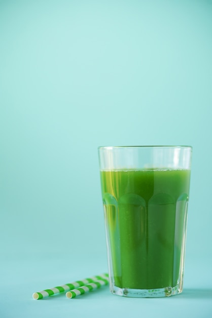 Glas groene selderiesmoothie op blauwe achtergrond