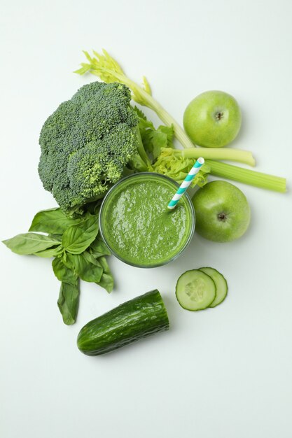 Glas groene smoothie en ingrediënten op witte achtergrond, bovenaanzicht