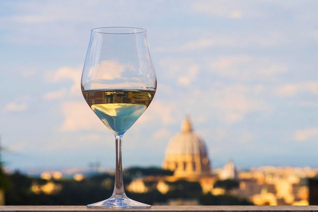 Glas Italiaanse witte wijn met de Sint-Pietersbasiliek Rome op de achtergrond