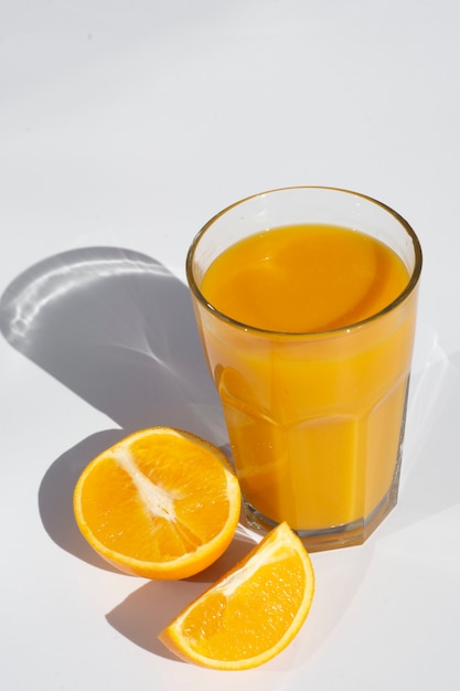 Glas jus d'orange met plakjes oranje diepe schaduwen geïsoleerd op wit