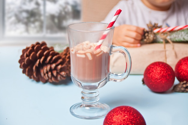 Glas kerstcacao met gestreept stro op de blauwe tafel.