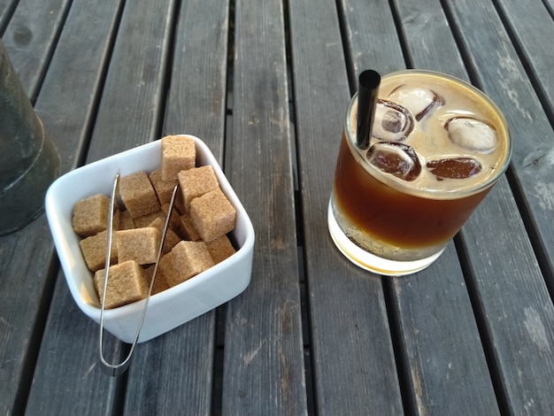 Foto glas koffie cocktail tonic espresso met ijs en suikerpot met bruine suiker op de houten tafel