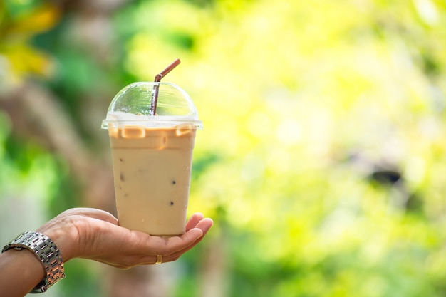 Glas koude espresso in de hand, wazig uitzicht boom.