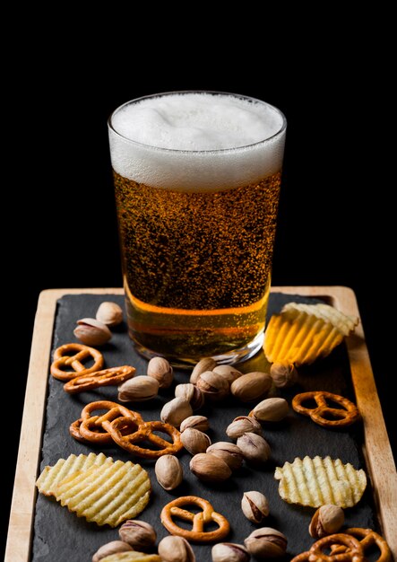 Glas lager bier met snacks op stenen bord met snacks