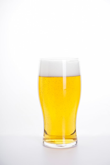 Glas licht bier dat op witte muur wordt geïsoleerd