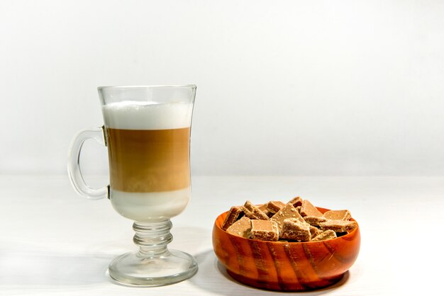 Glas macchiato latte met dulce de leche snoepjes.