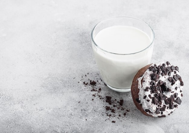 Glas melk en donut met zwarte koekjes op stenen keukentafel.