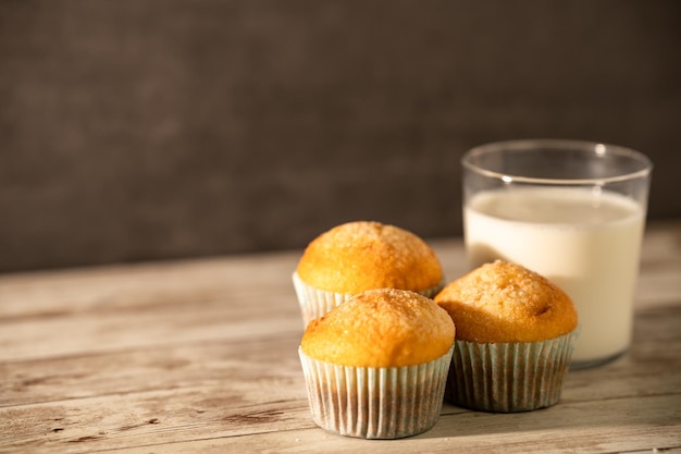 Glas melk met drie versgebakken muffins op de voorgrond ontbijt snack gebakjes concept