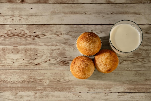 Glas melk met drie versgebakken muffins op de voorgrond ontbijt snack gebakjes concept