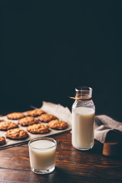 Glas melk met fles en havermoutkoekjes op perkamentpapier