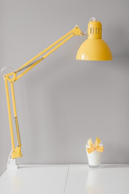 Glas melk met gele bowtie die zich op lijst onder lamp bevindt.