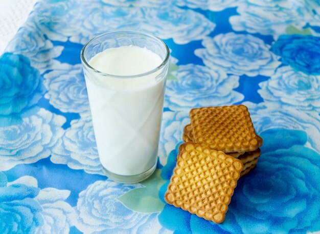 Glas melk met koekjes op blauwe achtergrond