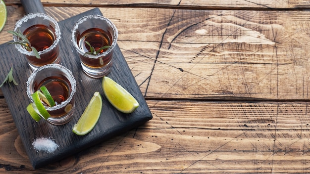 Glas met alcohol, zout en limoen op een houten achtergrond