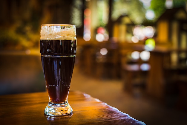 Glas met donkere soorten ambachtelijk bier op een houten bar