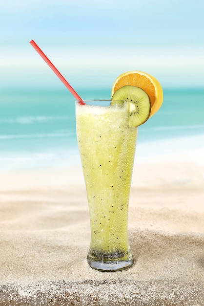 Glas met Kiwi en Jus d'orange op het strandzand