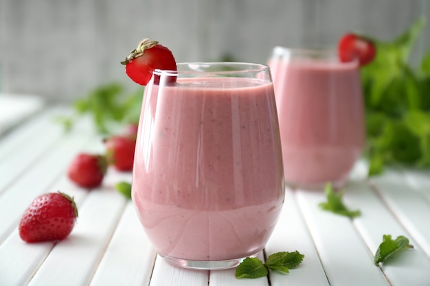 Glas met lekkere aardbeiensmoothie op houten tafel