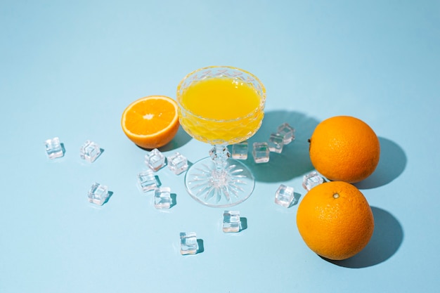 Glas met oranje cocktail, sinaasappel en ijsblokjes