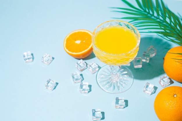 Glas met oranje cocktail, sinaasappel en ijsblokjes