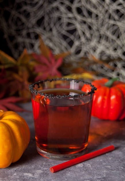 Glas met pompoencocktail met de herfstbladeren en pompoenen op de achtergrond