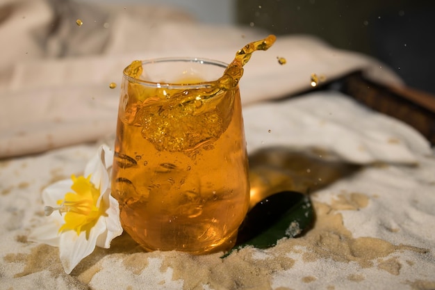 Glas met sinaasappeldrank op zandstrand