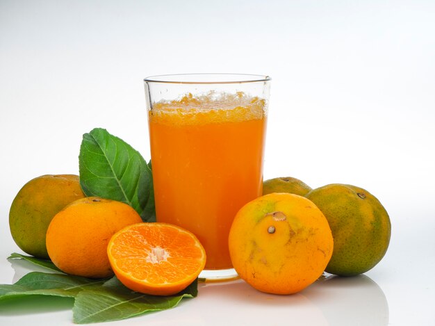 Glas met sinaasappelsap en fruit met groene bladeren