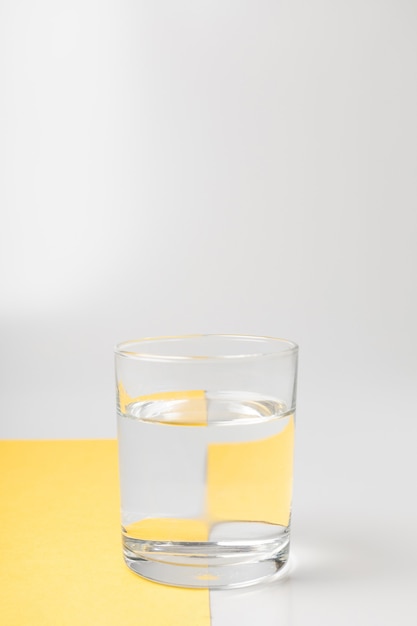Glas met water op grijze en gele achtergronden