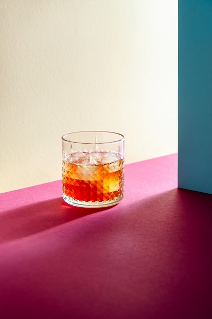 Glas met whisky en ijsblokje op tafel met harde schaduwen. Moderne isometrische stijl. Creatief concept