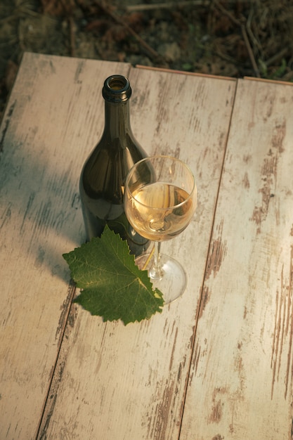 Glas met witte wijn in de wijngaard op oude tafel