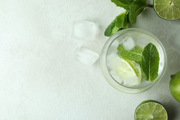 Glas mojitococktail en ingrediënten op witte geweven lijst