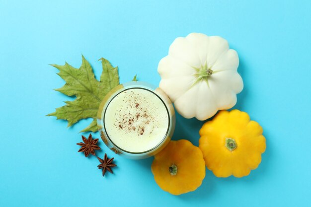 Glas pompoen latte en ingrediënten op blauwe achtergrond