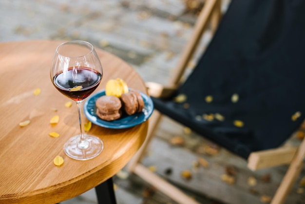 Glas rode wijn en bitterkoekjes op tafel buiten het terras met vallend geel blad. Herfst stemming concept