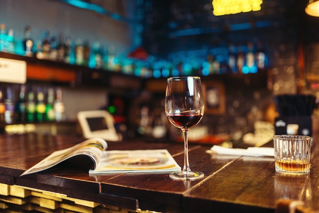 Glas rode wijn en geopende menu op houten toog. Nacht levensstijl concept