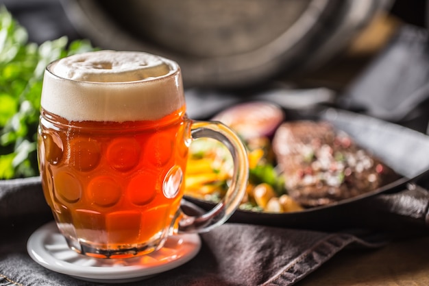 Glas rood bier in pub of restavurant op tafel met heerlijk eten.