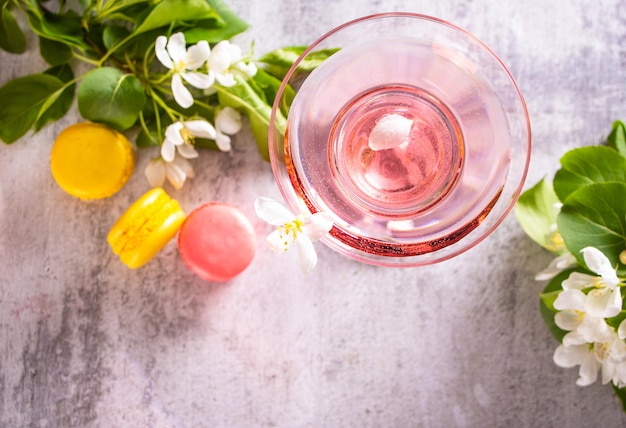 Glas roze cocktail met bloemen tak van appelboom en kleurrijke bitterkoekjes bruiloft of valentijnsdag romantisch datum paar concept bovenaanzicht