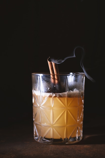 Glas Scotch Whisky sinaasappelsap alcohol cocktail met roken kaneelstokjes